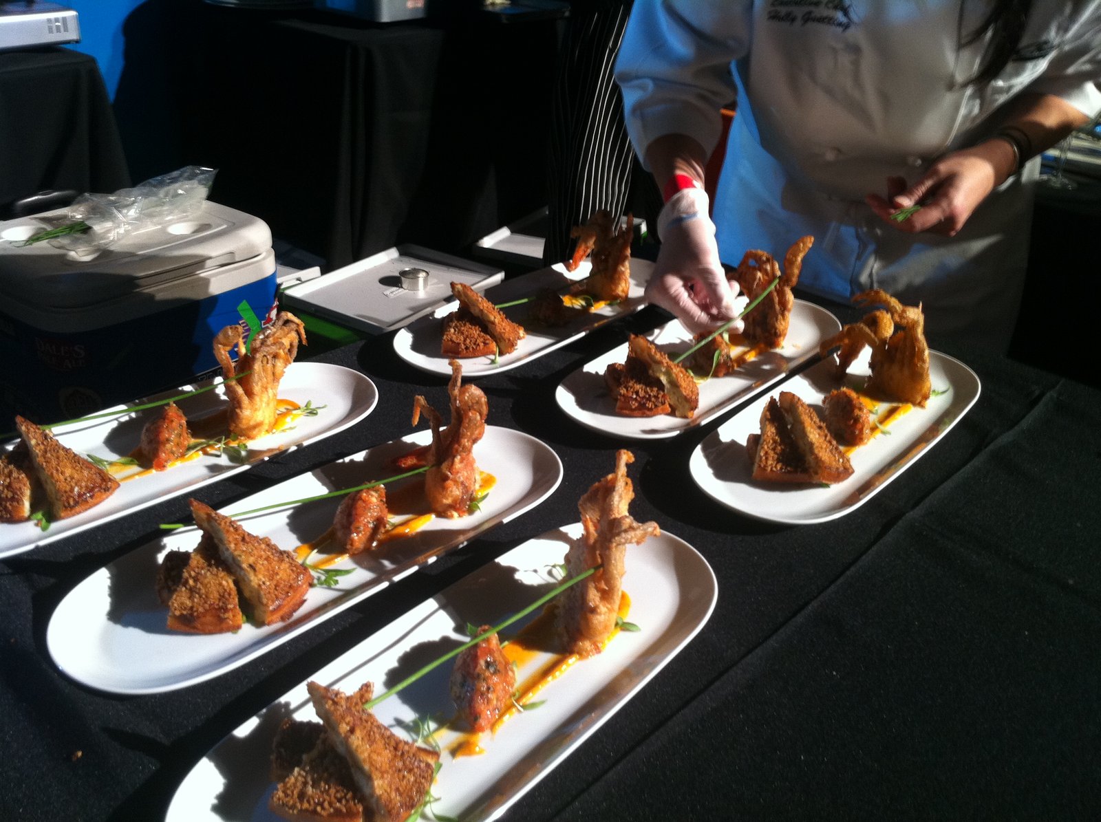 A chef plating seafood dishes at a cook-off event